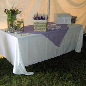 White rectangular tablecloth with a teal runner and flowers at a popup small business display