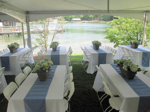 White wedding tablecloths with teal runners on tables in an backyard lakefront wedding reception 