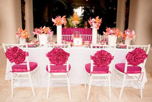 Formal Wedding linens on reception table with number card and pink flower type sashes on chairs