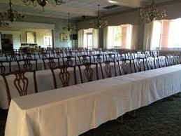 White formal linens on long tables in a classroom or speech-style indoor setting with chairs