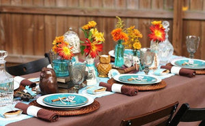 Formal Linens on a rectangular table during a backyard Thanksgiving dinner with plates & decorations