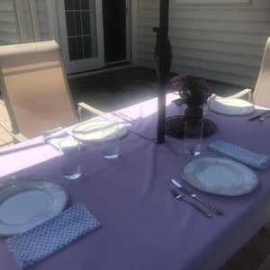 Blue table linens on an outdoor table with an umbrella and place settings