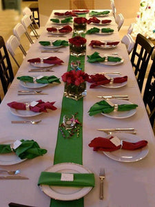 White formal linens with a green table runner and red and green napkins
