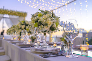 Close-up of an outdoor wedding reception table with napkins on plates and wine glasses 
