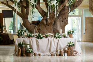 Fine linens on a lead Wedding reception table with a large tree behind it