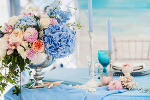 Light blue formal wedding tablecloth on table in an outdoor beach style setting with mixed flowers 