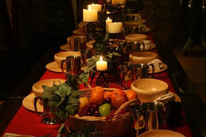 Fine linens on a Thanksgiving table with candles, plates, and fruit baskets