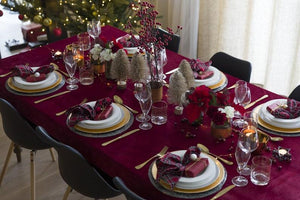 Red Velvet tablecloth on a Christmas  dinning table by a window with place settings and glasses