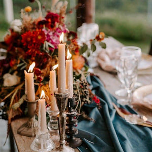 Velvet table runner on bare wooden table setting with candelabra and a harvest flower centerpiece