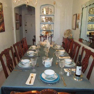 Fine linens on a family dinner table with napkins, cutlery, and a wine bottle