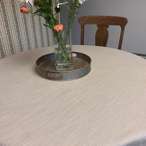 Formal linens on a round family dinner table with a flower vase and metal tray