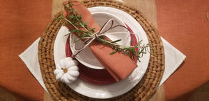 table linens on a Thanksgiving table with matching napkins rolled and tied with twine and a pumpkin
