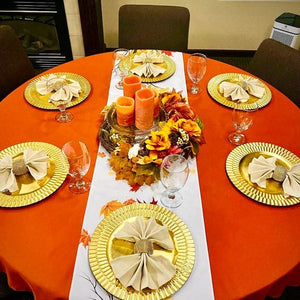 Formal linens on a round table with a white table runner and ivory napkins on gold plates