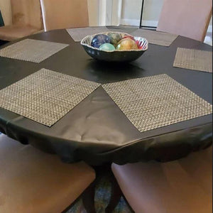 Brown vinyl table topper with elastic on a round table with placemats and centerpiece bowl