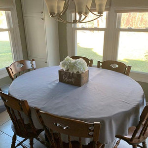 Charcoal Grey tablecloth on oval table in a home kitchen setting with a white bouquet of flowers