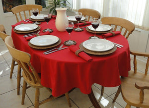 Oval Table with a red tablecloth with matching napkins, place settings, and wine glasses
