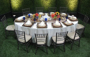 formal linens on an oval table with matching white napkins outdoors