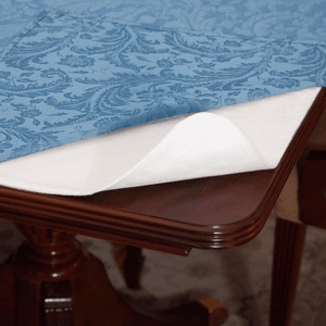 A white table pad is shown under table linens and slightly curled to show bendability