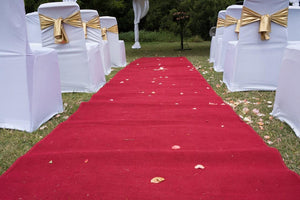 Red Velvet Aisle Runner down a wedding aisle outdoors with white chair covers and gold sashes